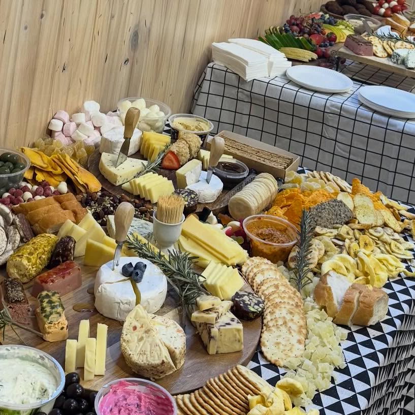 A grazing table catered by Salt n Pepa Cafe: brie, crackers, dips, dried fruit and cured meats on a checked cloth.